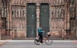 Une cycliste s'arrête pour consulter son téléphone, devant la cathédrale de Strasbourg, en mars 2020