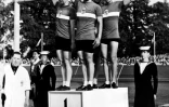 Charles Coste pose aux côtés de Pierre Adam, Serge Blusson et Fernand Decanali, sur la plus haute marche du podium des Jeux olympiques de Londres le 10 août 1948, après la victoire française à l'épreuve de poursuite par équipes