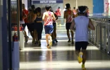 Des joggeurs courent à l’intérieur d’un centre commercial en raison du brouillard de pollution extérieur, le 24 octobre 2026 à Singapour
