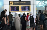 Des voyageurs regardent les tableaux d'information affichant les vols annulés après l'éruption du mont Lewotobi Laki-Laki, à l'aéroport international Ngurah Rai de Tuban, près de Denpasar, sur l'île touristique de Bali, le 18 juin 2025 en Indonésie