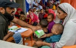Un travailleur social donne des médicaments à une mère après avoir examiné son enfant lors d'un programme de nutrition de l'Unicef au village de Fateh Muhammad Soomro, dans la province du Sindh, le 29 juillet 2025 au Pakistan