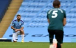 L'attaquant argentin de Manchester City Sergio Aguero (g) et le défenseur de Burnley James Tarkowski mettent un genou à terre en soutien au mouvement Black Lives Matter, le 22 juin 2020 à Manchester