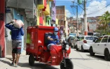 Un employé de Favela Brasil Xpress transporte des colis à livrer aux habitants de la favela Paraisopolis, le 1er décembre 2021 à Sao Paulo