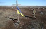 Un soldat ukrainien passe à côté d'un mémorial de fortune à Svetlodarsk, près de Donetsk, en Ukraine, le 12 mars 2022
