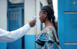 Un membre du personnel de l'hôpital CBCA Virunga prend la température d'une visiteuse à l'aide d'un thermomètre infrarouge sans contact avant de l'autoriser à entrer dans l'hôpital de Goma, en République démocratique du Congo, le 17 mai 2026.