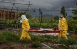 Des membres du personnel médical, en combinaisons de protection, transportent un patient sur une civière à l'hôpital de Rwampara, le 21 mai 2026 en RDC, lors d'une épidémie d'Ebola