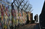 Des visiteurs passent devant une clôture militaire couverte de messages appelant à la réunification dans le parc de la paix Imjingak, près de la zone démilitarisée (DMZ) qui divise les deux Corées, à Paju, le 1er janvier 2021