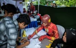 Des membres de bureaux de vote déguisés en superhéros à Surabaya en Indonésie, le 17 avril 2019