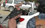 Un combattant taliban travaillant comme policier vérifie le coffre d'une voiture le 3 octobre 2021 à Kaboul