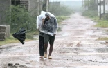 Des habitants se protègent avec un sac plastique d'une forte pluie à l'approche du cyclone Arnab, le 27 octobre 2026 à Kakinada, dans l'Etat de l'Andhra Pradesh, en Inde