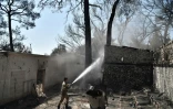 Un pompier grec lutte contre le feu sur un site abandonné du Club Méditerranée à Lambiri, près de Patras, le 1er août 2021