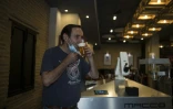 Le propriétaire du bar Gitana Loca, Alberto Martinez, boit une bière servie par un robot, le 17 mai 2020 à Séville, en Espagne