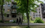 Deux hommes marchent près de bâtiments endommagés à Lyman, dans l'est de l'Ukraine, près de la ligne de front, le 7 mai 2025