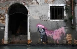 Une oeuvre de l'artiste de rue Banksy, représentant un enfant migrant avec un gilet de sauvetage et une fusée de détresse, sur un mur d'une rue inondée, à Venise le 13 novembre 2019