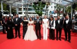 Le réalisateur iranien Mohammad Rasoulof, au centre, brandit les photos de l'acteur iranien Missagh Zareh, à gauche, et de l'actrice iranienne Soheila Golestani, à droite, le 24 mai 2024, au festival de Cannes, dans les Alpes-Maritimes