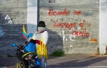 Une femme indigène se tient près d'une inscription murale disant "L'Equateur avec la corde au cou", dans un jeu de mots avec le nom du président Guillermo Lasso, à Quito, le 21 juin 2022