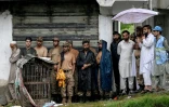 Des sauveteurs et du personnel militaire s'abritent de la pluie sous le toit d'un bâtiment alors que le niveau des eaux de crue monte dans le district de Buner, dans la province  de Khyber Pakhtunkhwa, le 18 août 2025 au Pakistan