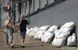 Des habitants passent devant la mairie dont les fenêtres du sous-sol sont protégées par des sacs de sable, à Koursk, le 16 août 2024 en Russie