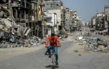 Un homme passe en vélo au milieu des immeubles détruits dans une rue de la ville de Gaza le 27 mars 2024