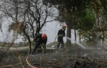 Les pompiers refroidissent le sol à proximité d'une école, à la suite d'un incendie de forêt dans la banlieue de Tres Cantos, au nord de Madrid en Espagne, le 12 août 2025
