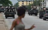 Une femme regarde les soldats ivoiriens qui patrouillent près du quartier général de l'armée, le camp militaire de Gallieni, à Abidjan le 12 mai 2017