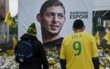 Des supporters nantais observent les bouquets de fleurs, messages et bougies placés sous un portrait d'Emiliano Sala devant le stade de la Beaujoire avant le match de championnat contre Saint-Etienne, le 30 janvier 2019 à Nantes