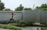 Des enfants sautent dans un canal d'irrigation qui traverse le village de Kolkhozobod, dans le sud-ouest du Tadjikistan, le 27 août 2025
