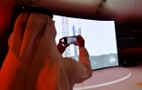 Un homme prend une photo de l'écran montrant le lancement de la sonde émiratie Al-Amal en route pour Mars depuis le Japon, le 19 juillet 2020 au Centre spatial Mohammed bin Rashid (MBRSC) de Dubaï
