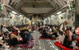 Des Afghans s'installent dans un avion militaire américain qui va les évacuer d'Afghanistan, à l'aéroport de Kaboul, le 19 août 2021
