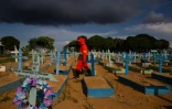 Un employé de pompes funèbres au milieu de tombes de victimes du Covid-19 dans un cimetière de Manaus (Brésil), le 29 avril 2021