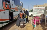 Des personnes attendent avec leurs bagages devant un bus à Khartoum pendant des combats entre l'armée et les paramilitaires, le 8 mai 2023 au Soudan