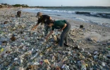 Des personnes fouillent dans des ordures et déchets plastiques échoués sur la plage de Kedonganan, sur l'île indonésienne de Bali, le 19 mars 2024