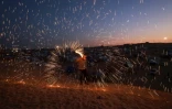 Un jeune Palestinien joue avec un feu d'artifice dans un camp de déplacés à Rafah, dans le sud de la bande de Gaza, à la veille du mois sacré de ramadan, le 10 mars 2024