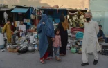 Une femme portant une burqa (c) devant un étal d'un marché de Kaboul, le 25 août 2021
