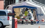 Des médecins s'occupent d'un patient arrivant à l'accueil des Urgences, dans une cour de l'hôpital Henri Mondor à Créteil, près de Paris, le 26 mars 2020, au dixième jour d'un confinement visant à enrayer la propagation du Covid-19 en France