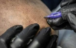 Remy, tatoueur professionnel, réalise une intervention de micropigmentation du cuir chevelu sur un client, dans son studio de Ginowan, à Okinawa au Japon, le 19 mai 2026