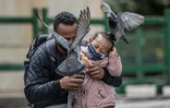 Un homme et sa fille masqués nourrissent des pigeons à Bogota le 3 juillet 2020.