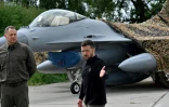 Le président ukrainien Volodymyr Zelensky (D) devant un chasseur F-16 lors d'une cérémonie dans un lieu tenu secret en Ukraine, le 4 août 2024