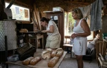 Des femmes font cuire du pain dans un four du "Quartier libres des Lentillères", une ZAD urbaine à Dijon, le 14 août 2025 en Côte d'Or