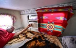 Elbert Yazzie règle son climatiseur dans sa caravane, après l'installation récente de l'électricité sur son terrain à Tuba City, en Arizona, le 8 juillet 2025 