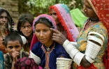 Une villageois en tenue traditionnelle montre un tatouage indigène encré sur le visage de Reshma (c) dans le village de Ponjo Kolhi, près d'Umerkot, un district à majorité hindoue, le 14 juillet 2025 au Pakistan