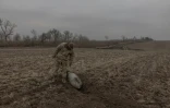 Un démineur de l'armée ukrainienne inspecte une bombe aérienne guidée russe non explosée dans un champ de la région de Dnipropetrovsk, le 30 janvier 2025
