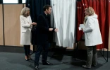 Le président français Emmanuel Macron et son épouse Brigitte Macron s'entretiennent avec une électrice avant de voter au premier tour de la présidentielle, le 10 avril 2022 au Touquet 