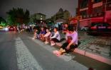 Des habitants assis dans la rue après un séisme de magnitude 5,4, le 6 août 2023 dans la localité de Dezhou dans l'est de la Chine 