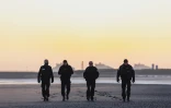 Des policiers français patrouillent sur la plage de Gravelines au lever du soleil afin d'empêcher les migrants de traverser la Manche, à Gravelines, dans le nord de la France, le 14 avril 2026