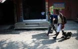 Le migrant vénézuélien Gilberto (d) et son chien Negro, en compagnie d'un autre migrant, dans une rue de Tecun Uman, le 17 mai 2022 au Guatemala, à la frontière avec le Mexique 