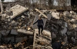 Un policier marche dans les ruines d'une maison détruite dans le village de Bohdanivka , au nord-est de Kiev, le 14 avril 2022