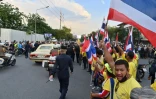 Des partisans pro-royalistes agitent le drapeau thaïlandais lors du passage du cortège royal, le 14 octobre 2020 à Bangkok 