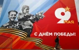 Une femme passe devant une affiche célébrant le "jour de la Victoire" pour les commémorations du 81 anniversaire de la capitulation allemande en 1945, le 6 mai 2026 à Moscou
