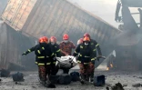 Des pompiers portent le corps d'une victime d'un incendie dans un entrepôt de conteneurs, le 5 juin 2022 à Sitakunda, au Bangladesh